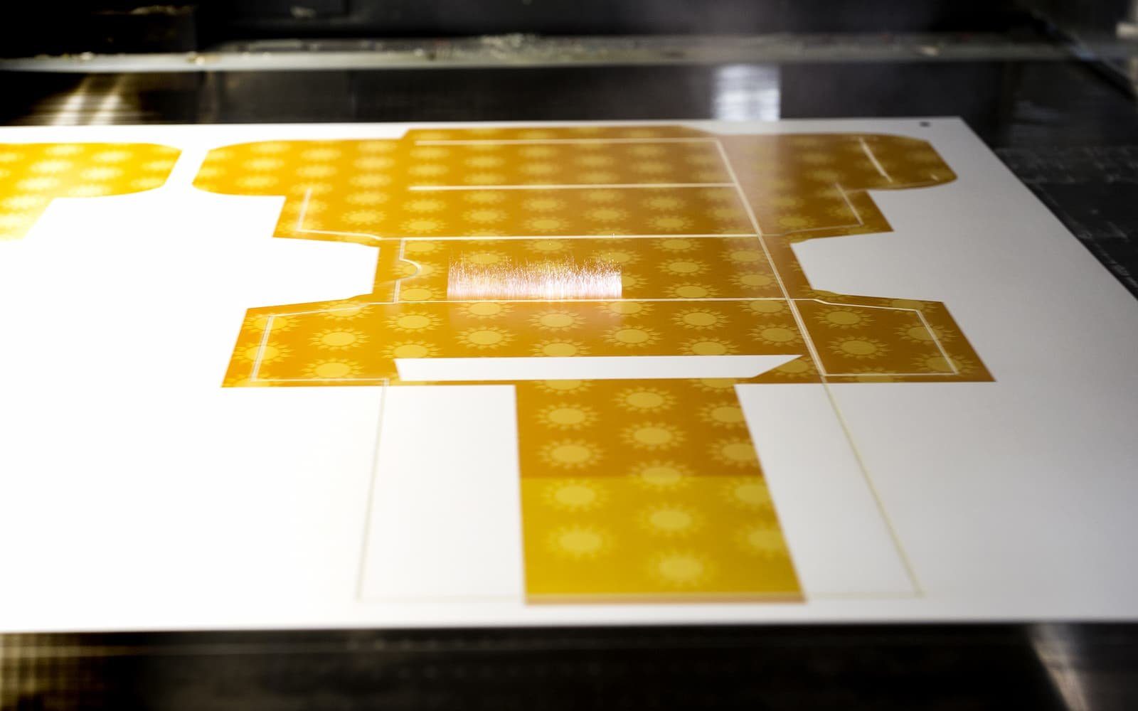 Laser cutting an intricate gold pattern sheet on the cutting bed