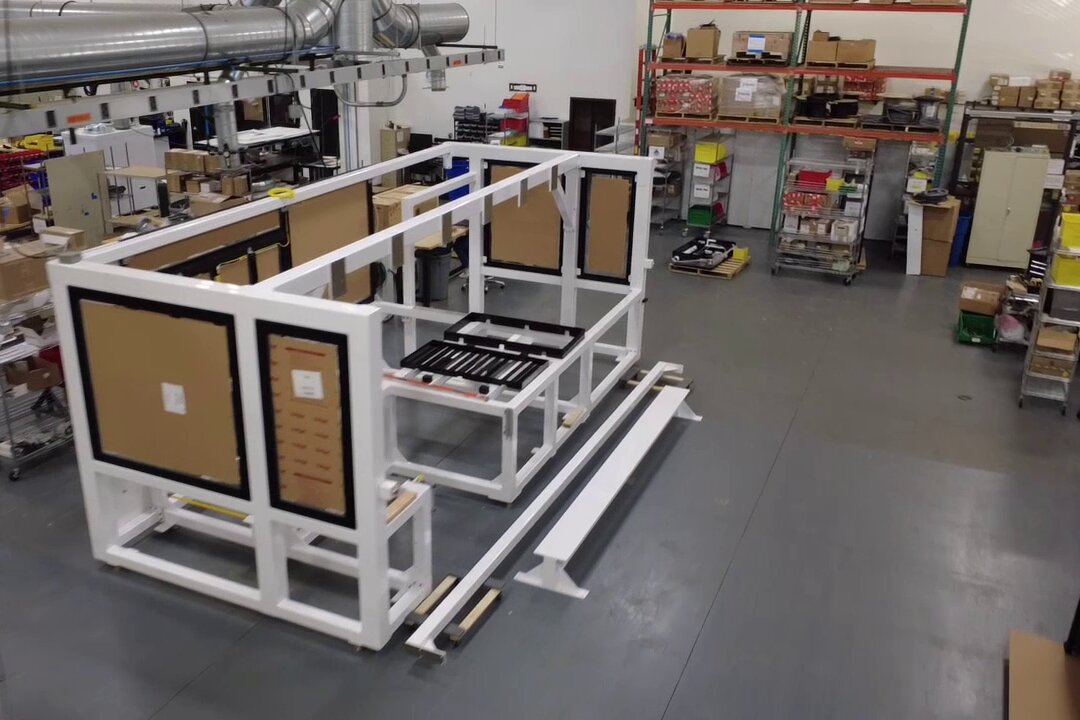 A white machine frame being assembled on the LasX build floor