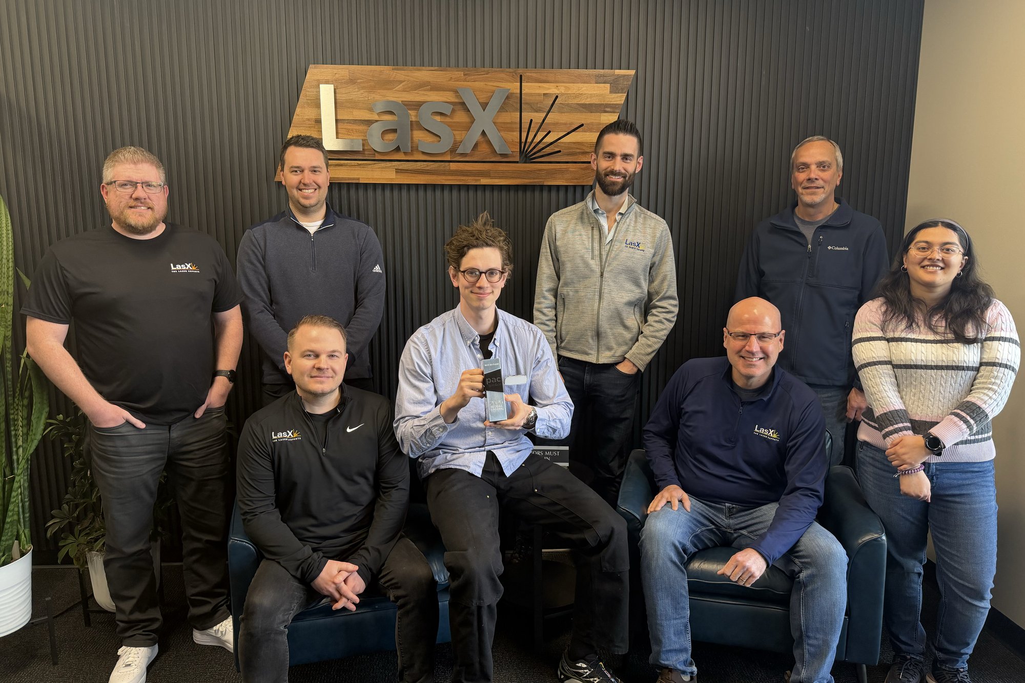 LasX team members gathered in front of the LasX logo wall