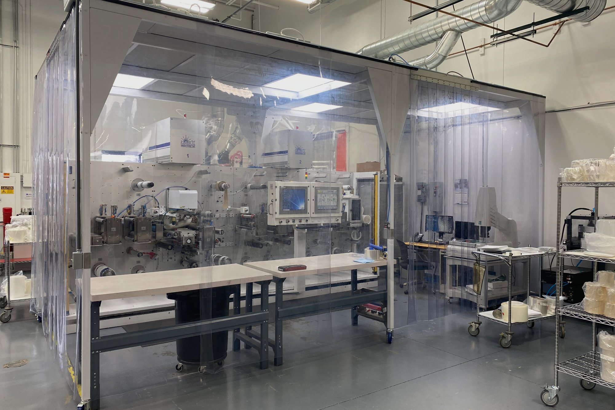 Softwall cleanroom with workbenches and laser equipment on the LasX contract manufacturing floor