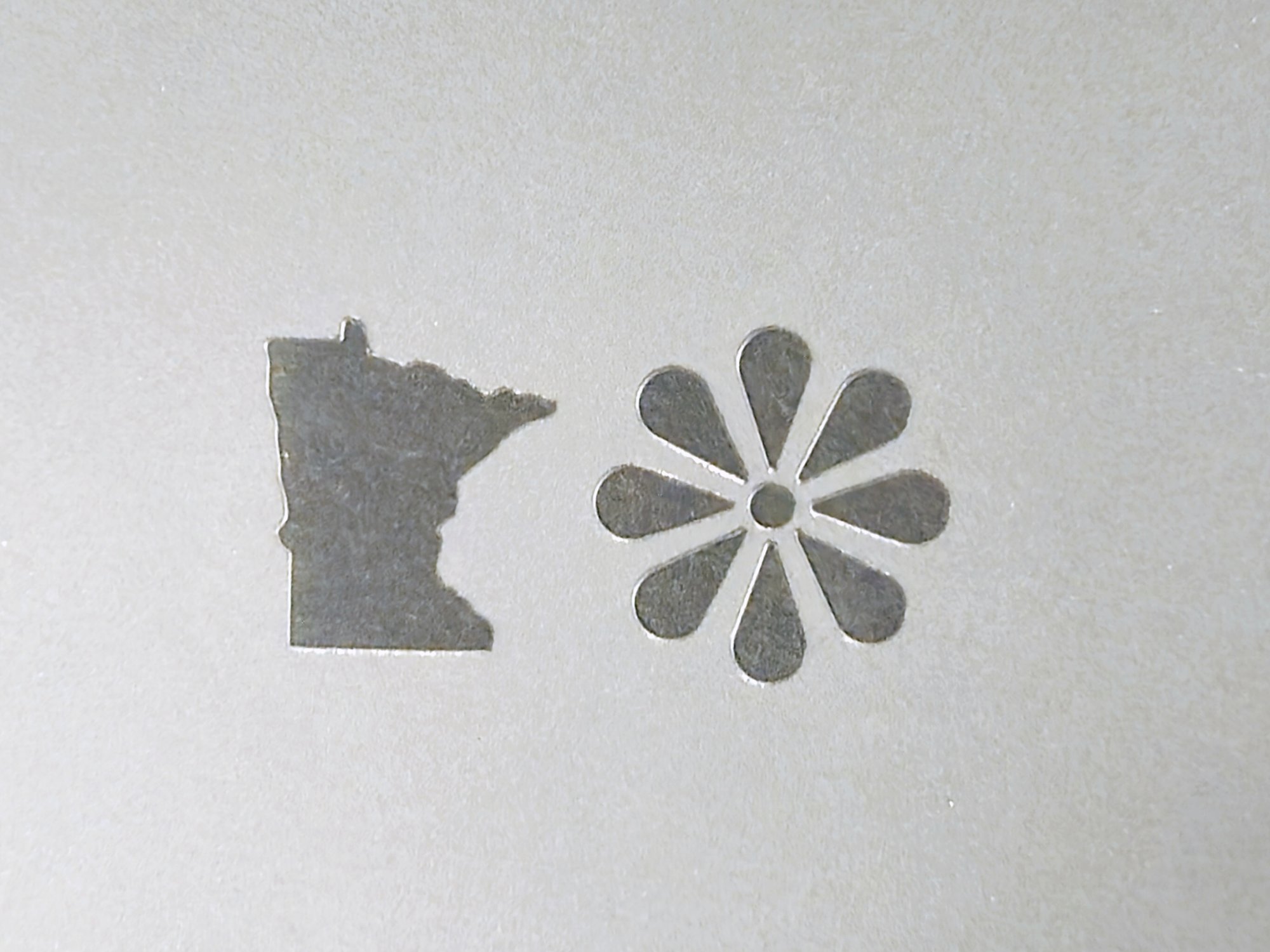 A Minnesota outline and an eight-petal flower, laser-cut as windows in clear polycarbonate film