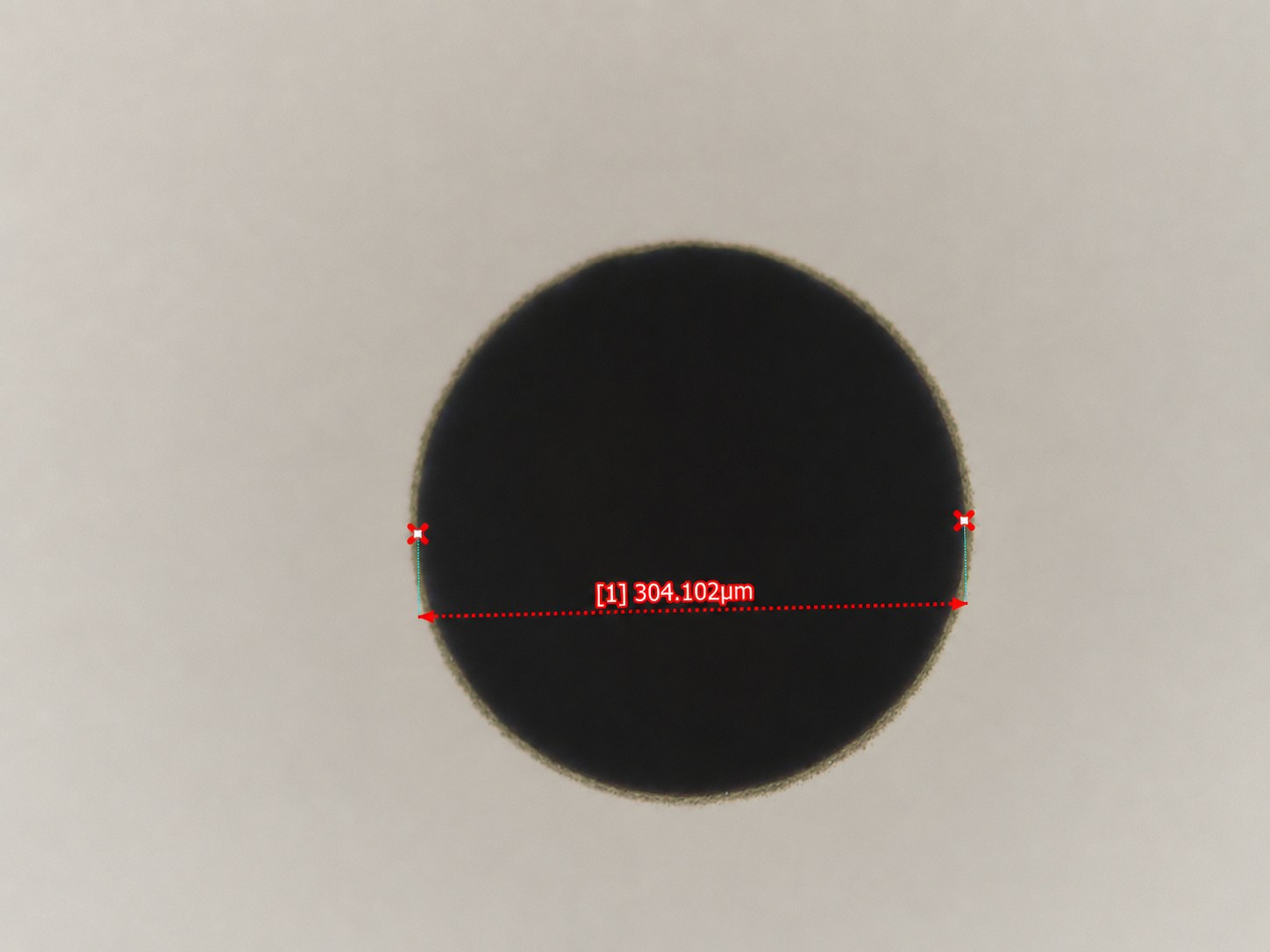 Single laser-drilled through-glass via in reflected light, measured at 304 µm