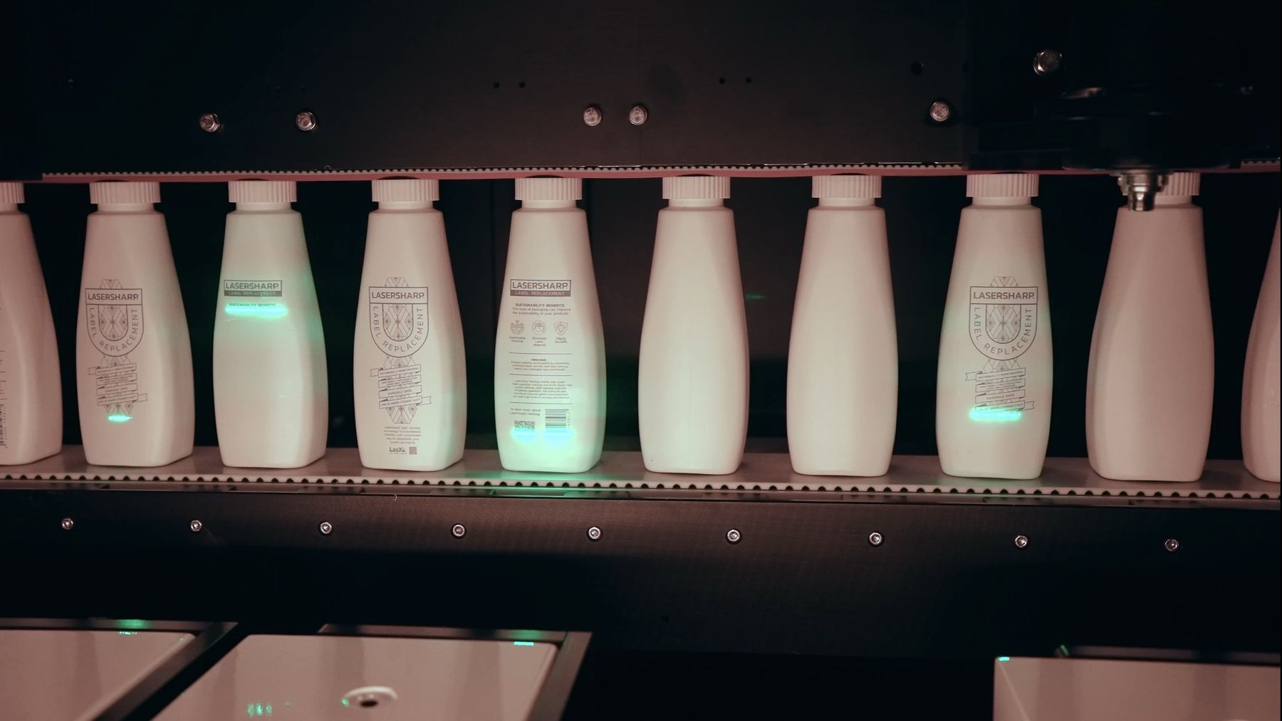 Bottles on a conveyor receiving label-replacement marks inline