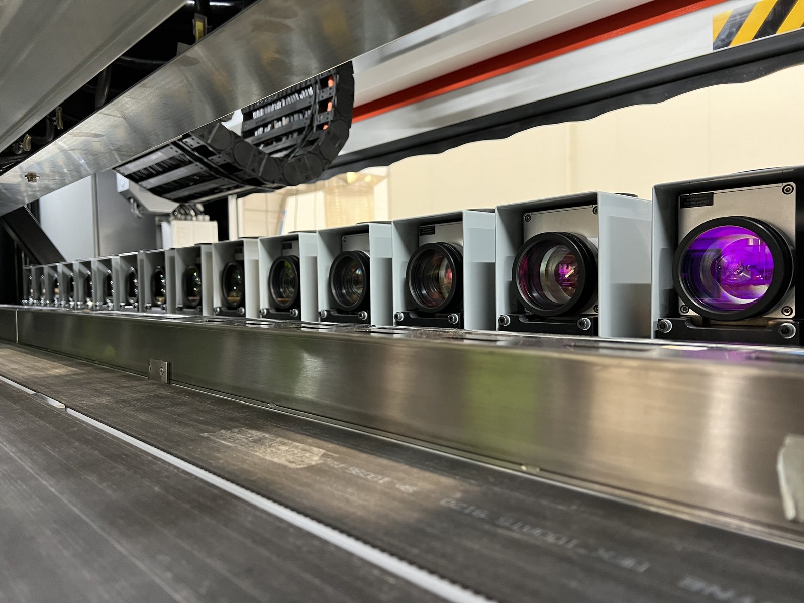 A bank of LaserSharp Marking scan heads in a row along the marking line, lenses toward the product path
