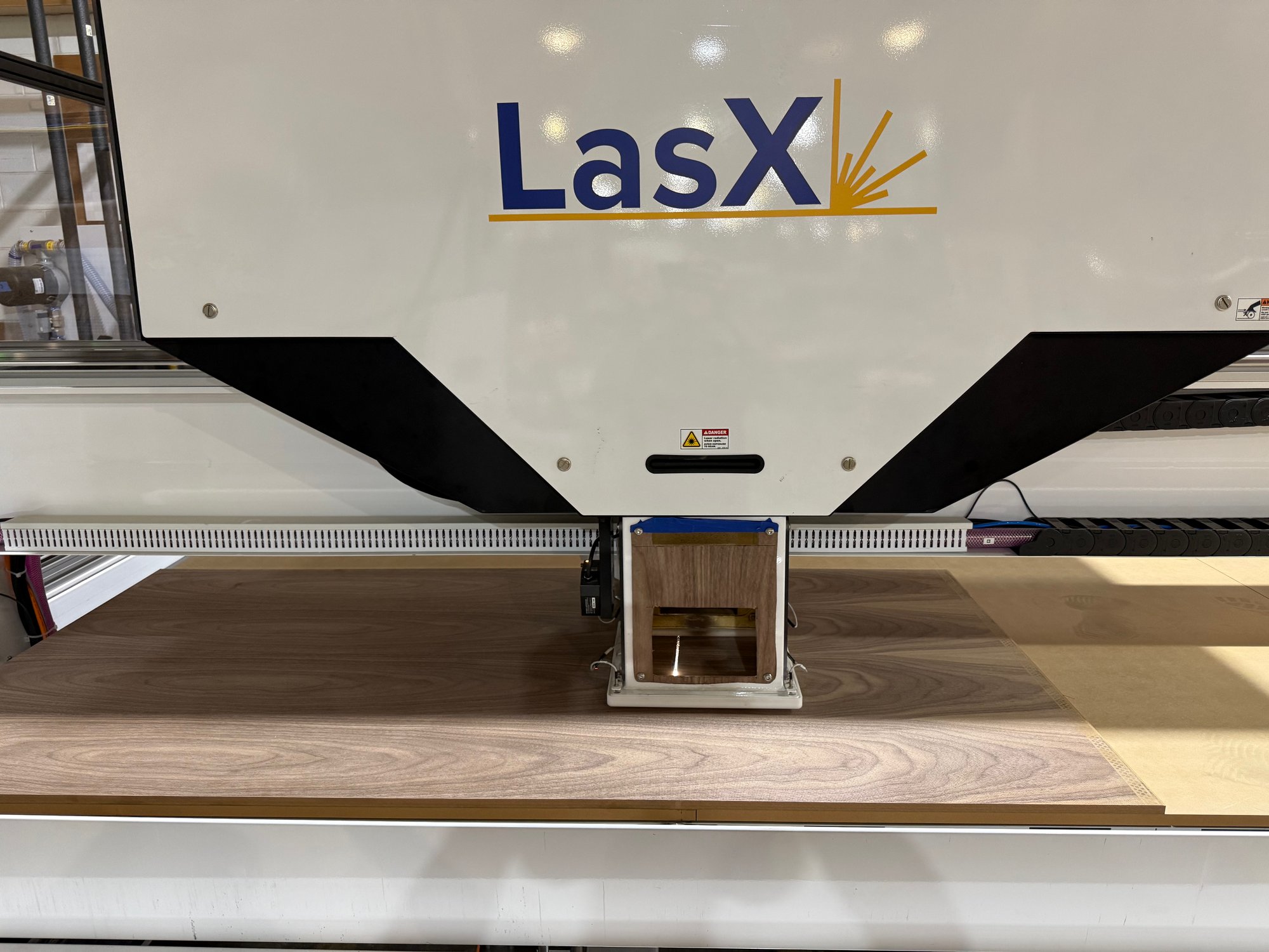 LaserSharp LPM on the SheetPro gantry, positioned over a walnut-veneer board on the static bed