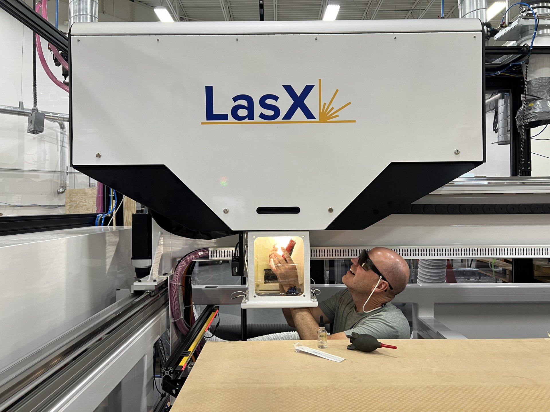 A LasX engineer in laser safety glasses checks the optics at the LaserSharp LPM on a SheetPro gantry