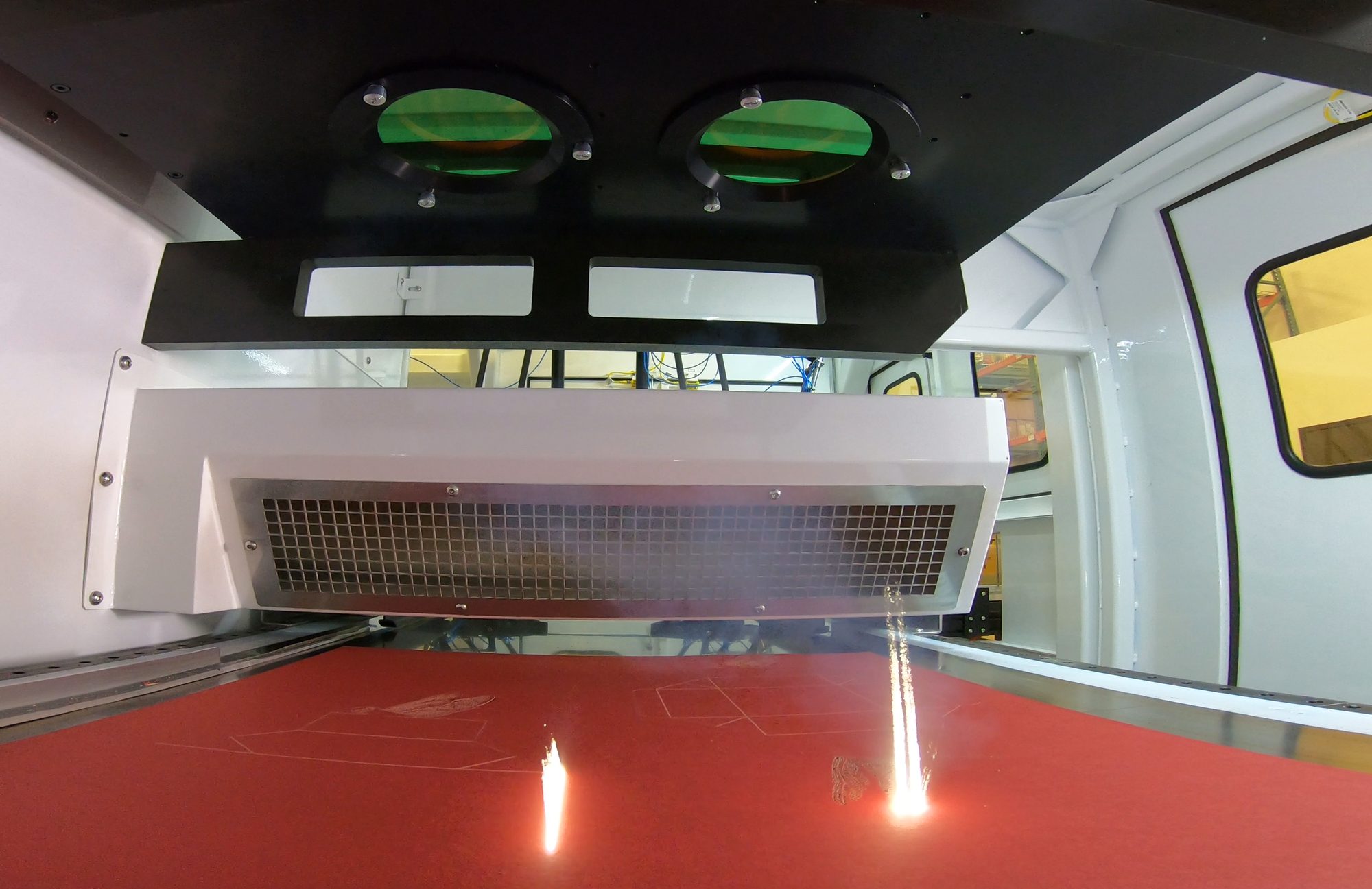 Laser processing a red board inside a SmartFinish laser cell, with the process plume visible