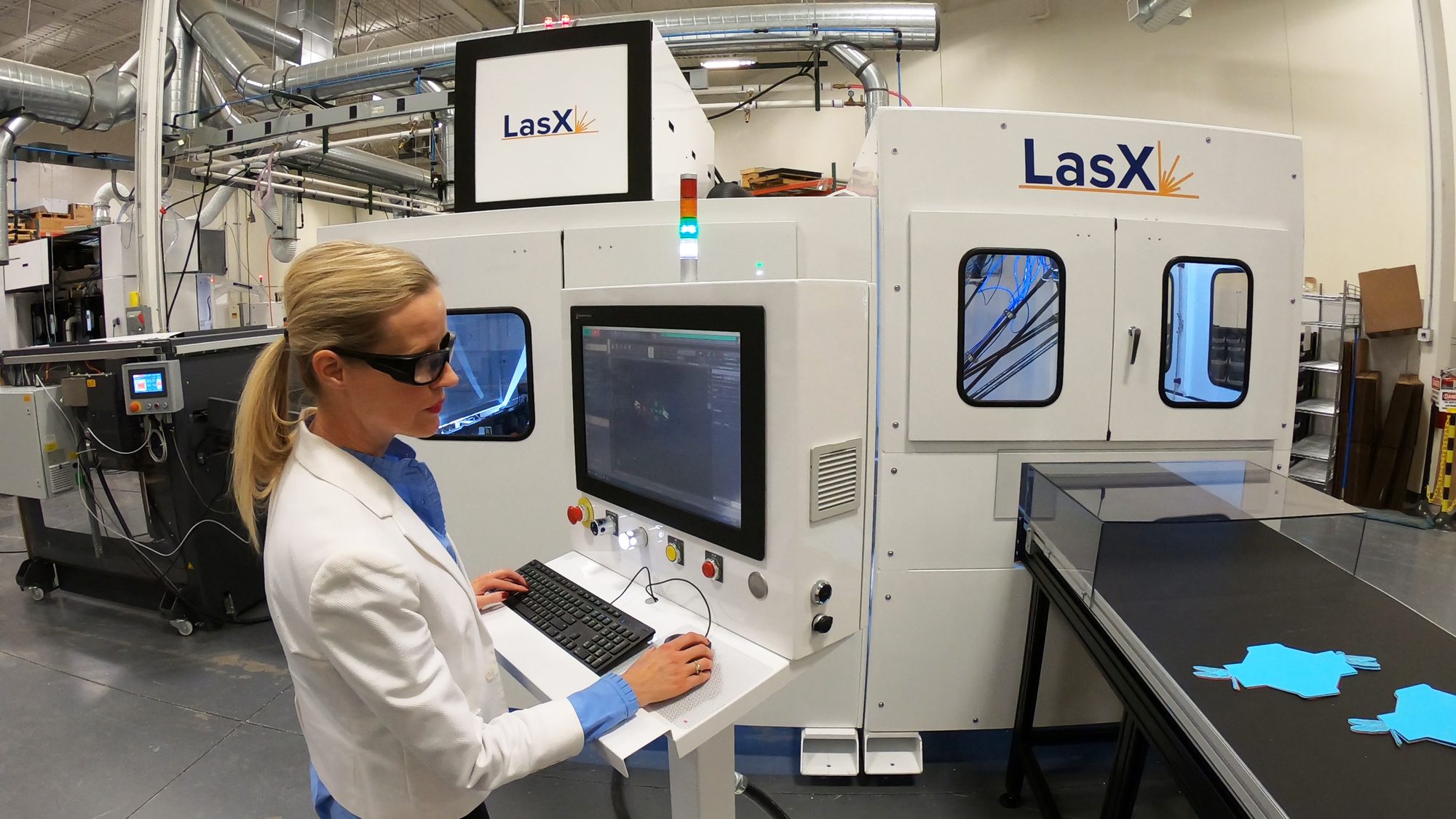 Operator at a LightGuide HMI beside two LasX machines